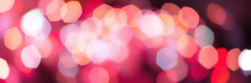 Vibrant bokeh lights in red, pink, and white illuminate a lively setting during a nighttime event. The colorful arrangement enhances the festive mood for attendees.