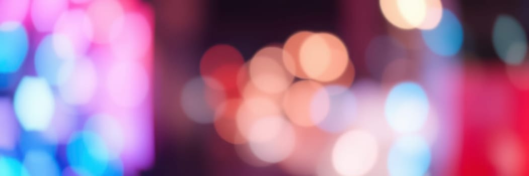 Bright, colorful lights illuminate a city street, creating a lively and energetic ambiance. The vibrant hues blend together, adding a festive touch to the night.