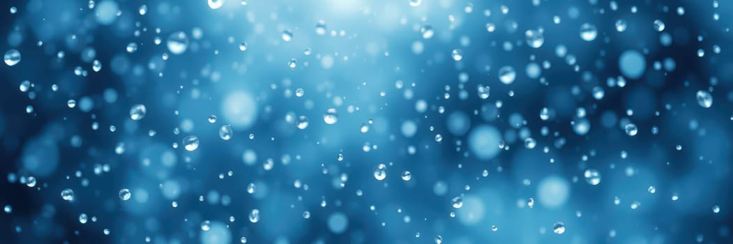 Gentle raindrops fall softly, creating ripples and shimmering reflections on a blurred blue surface. The atmosphere feels calming and refreshing on this cool evening.