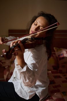 A woman immersed in playing her violin, showcasing emotion and concentration. The soft lighting enhances the intimate atmosphere, capturing the essence of musical passion and dedication.