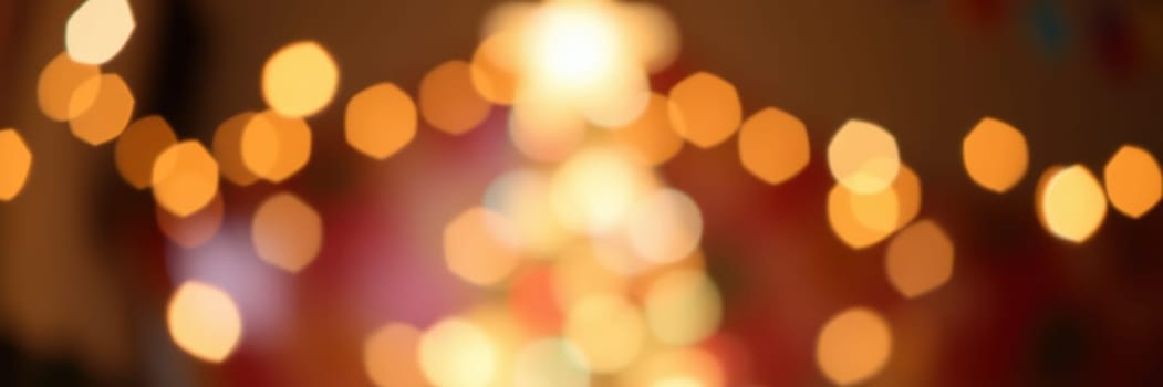 Softly blurred lights from a beautifully decorated Christmas tree enhance the festive spirit in a warmly lit room. The atmosphere evokes joy and celebration during the holiday season.
