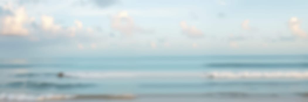 Early morning at a tranquil beach where calm waves lap against the shore and soft clouds float in the bright blue sky. A peaceful natural setting for reflection and relaxation.