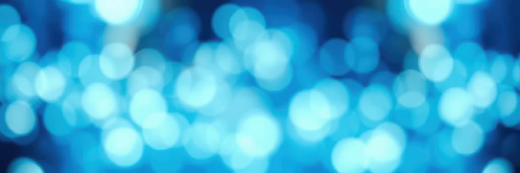 Soft blue bokeh lights shimmer and dance, adding a magical touch to an evening celebration. The colorful illumination sets a festive mood during the night.
