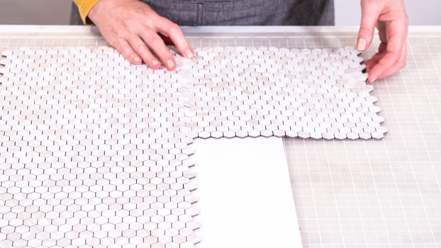 In the process of mounting peel and stick mosaic tiles onto a foam board, perfect for enhancing a food photography studio's aesthetic.
