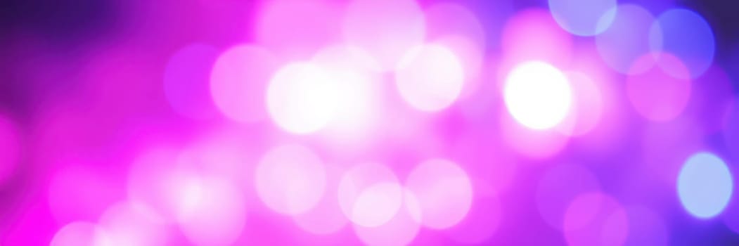 Soft, blurred lights blend shades of pink, purple, and blue, creating an enchanting ambiance at a night event filled with joy and excitement.