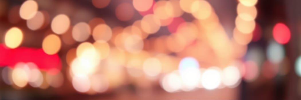 Colorful bokeh lights illuminate the city streets as people gather for a nighttime celebration. The vibrant atmosphere is filled with excitement and joy as festivities unfold.