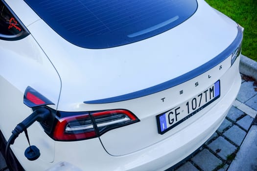 Cremona, Itally - October 6th 2024 Close-up shot of a white tesla model 3 being charged, highlighting sustainable transportation and electric vehicle technology