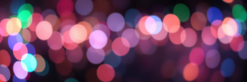 Softly blurred lights in various colors illuminate the night, creating a joyful and vibrant ambiance for a nighttime event or celebration.