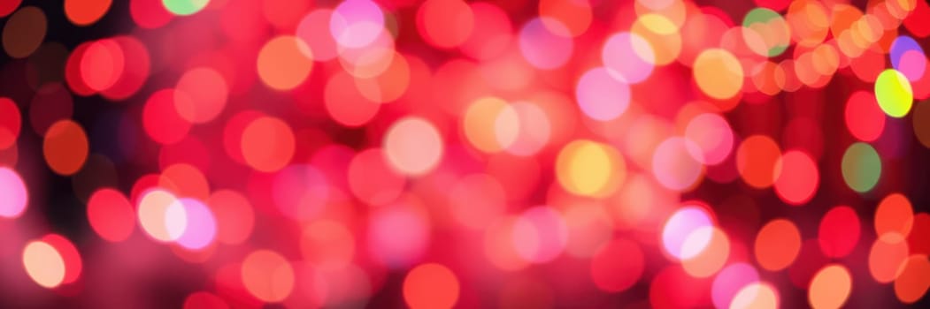 Colorful bokeh lights in various shades of red, pink, and yellow fill the background, creating a joyful ambiance for a nighttime event or celebration.