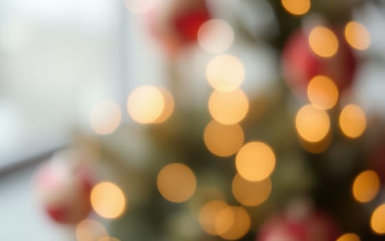 A beautiful Christmas tree adorned with twinkling lights and ornaments fills a cozy indoor space with a soft, inviting glow. The atmosphere is festive and cheerful.