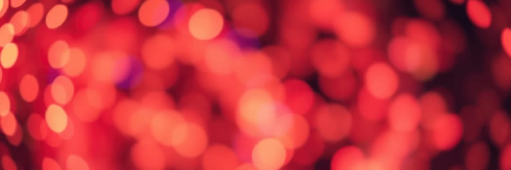 Red bokeh lights fill the background, creating a warm and inviting atmosphere at a festive gathering held in the evening. The blurred lights enhance the celebratory mood.