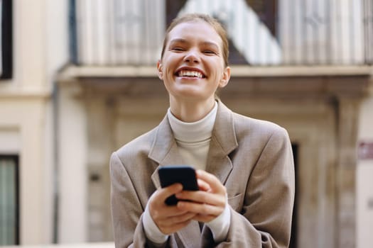 A joyful woman smiles brightly while checking her smartphone in an urban outdoor setting, radiating pure happiness and confidence, making the moment one of connection and delight in life