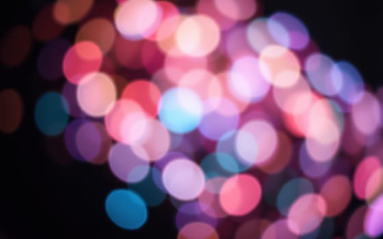 A collection of blurred, colorful lights forms a dynamic bokeh effect, enhancing the joyful ambiance of a summer celebration at night, filled with excitement and energy.