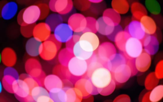 Bright, bokeh lights in various colors illuminate the space, adding a cheerful and festive ambiance to a celebration taking place at night.