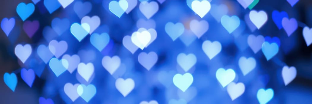 Ethereal heart-shaped lights softly glow against a blue backdrop, enhancing the enchanting ambiance during a nighttime event filled with joy and celebration.