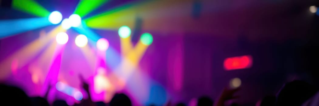 Vibrant beams of colored lights illuminate a crowd at a concert, filled with energy and excitement as people enjoy the live music performance late at night.