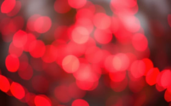 Blurred red lights fill the frame, creating a warm, radiant background that suggests a lively celebration or gathering. The soft focus enhances the colorful ambiance.