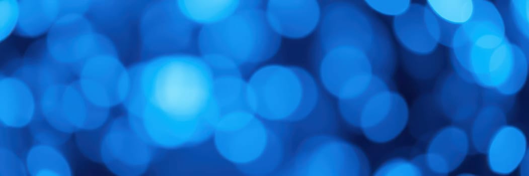 Soft blue lights blur into a captivating bokeh background, creating a magical ambiance for guests gathered outdoors during the night.