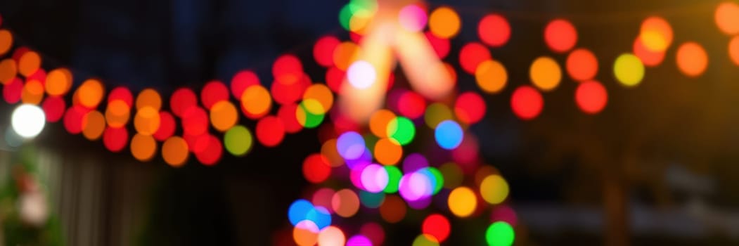 Bright, colorful lights adorn trees and decorations in a joyful outdoor setting during a winter evening gathering that celebrates the holiday spirit.