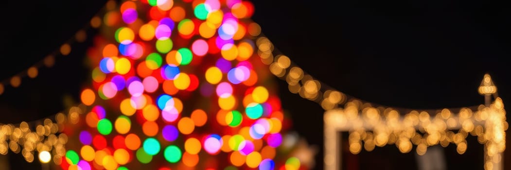 Colorful lights adorn a large Christmas tree, creating a joyful atmosphere. Strings of bright lights twinkle in the evening, enhancing the festive spirit around the cheerful gathering.