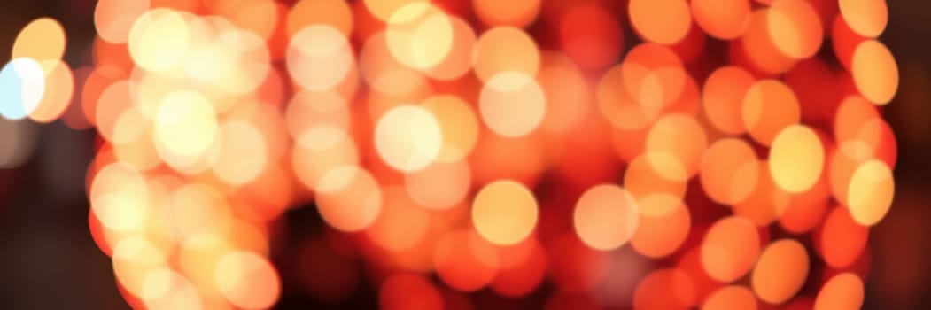 Soft, warm orange bokeh lights illuminate the surroundings, creating a cozy and inviting ambiance during a festive evening gathering in the urban area.