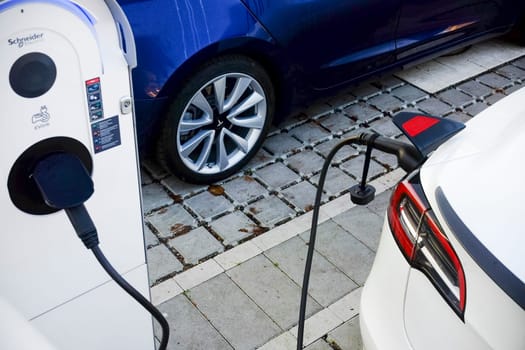 Cremona, Itally - October 6th 2024 White tesla model 3 long range dual motor all-wheel drive charging its battery at a schneider electric evlink charging station