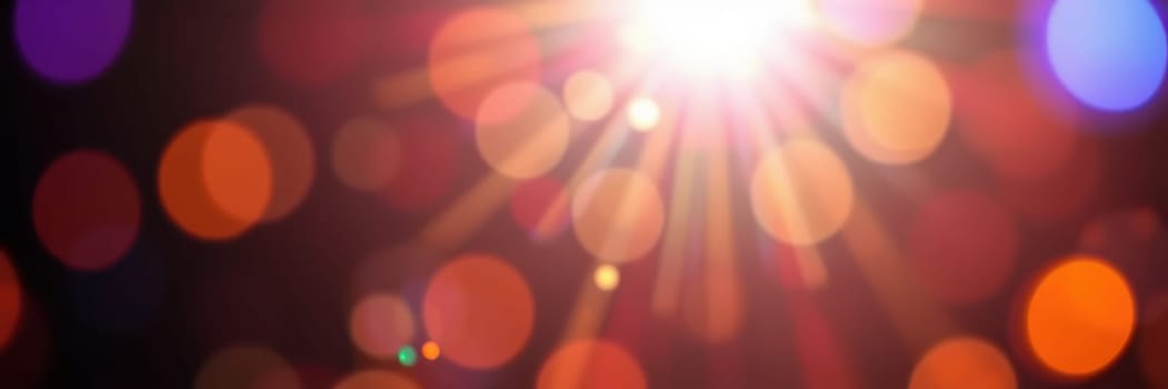 Vivid rays of light burst through a blurred background of colorful bokeh, enhancing the magical atmosphere of a nighttime celebration or gathering.
