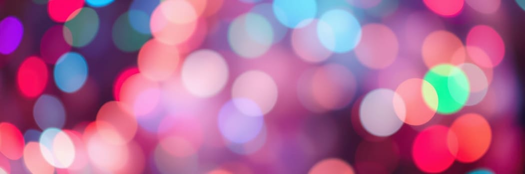 Bright, vibrant lights in various colors create a bokeh effect that adds a festive ambiance to a social gathering during the evening hours.