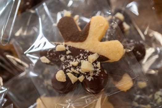 Carefully packaging Christmas cutout cookies, half-dipped in chocolate and presented in clear cellophane wrapping, perfect for festive gifting.