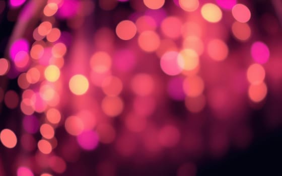 Soft, blurry lights in vibrant shades of pink and purple fill the background, enhancing the ambiance of a lively gathering during a cool autumn night.
