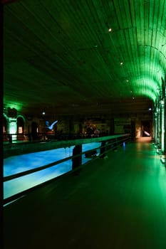 A contemporary indoor pool area that beautifully showcases mesmerizing green lighting and a sleek wooden design
