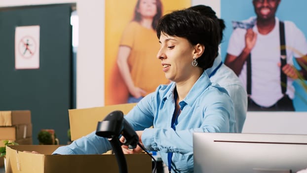 Diverse store employees working at online orders, putting trendy clothes in cardboard boxes waiting for courier in modern boutique. Workers preparing packages for delivery in shopping mall