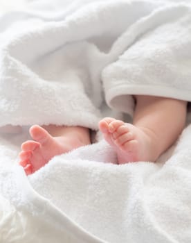 The feet of a newborn pure and soft peek from a white towel symbolizing life's gentle start after a calming bath