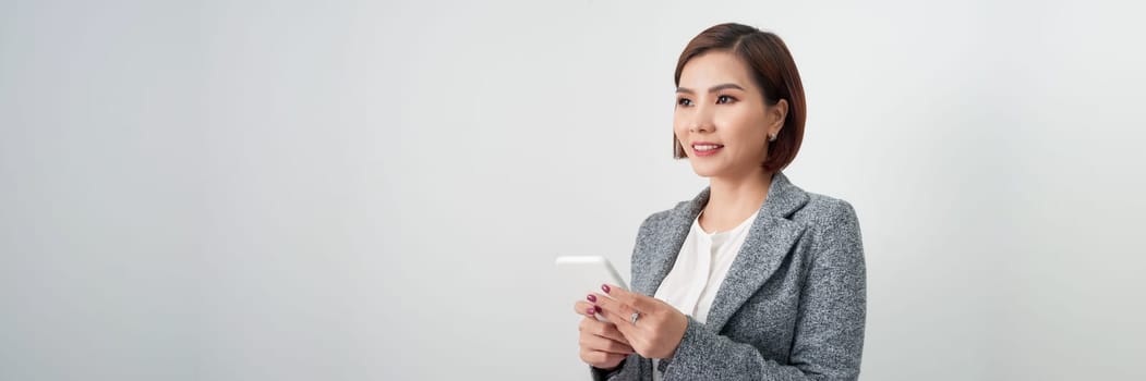 Banner of a happy asian businesswoman holding mobile phone isolated over white background