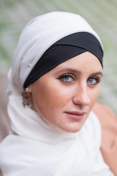 Portrait of a young blue-eyed woman in a hijab outdoors