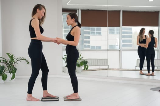 Caucasian and Asian women stand up sadhu boards together