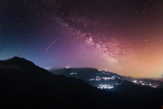 Night long exposure shot showing fog rolling over hills with village in distance showing prestine hills of darjeeling, shimla, manali, landsdowne India