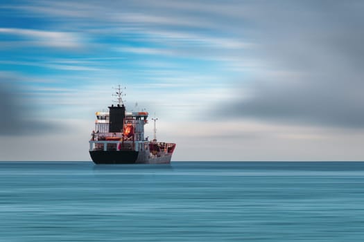 Transport ship traveling in open sea in cloudy weather.