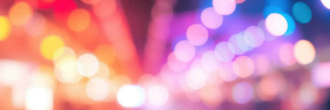 Bright, vibrant lights in various colors create a lively atmosphere at an outdoor gathering in the evening. The soft focus adds to the festive feel surrounding the event.