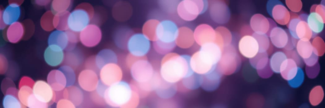 A vibrant display of blurred lights illuminates the space, creating a joyful mood during evening festivities at a community gathering.