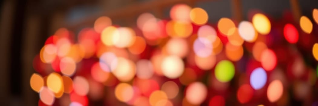 Bright, colorful lights twinkle and blur together, setting a warm ambiance for a winter festival in a city park. People gather, enjoying the festive decorations and holiday spirit.