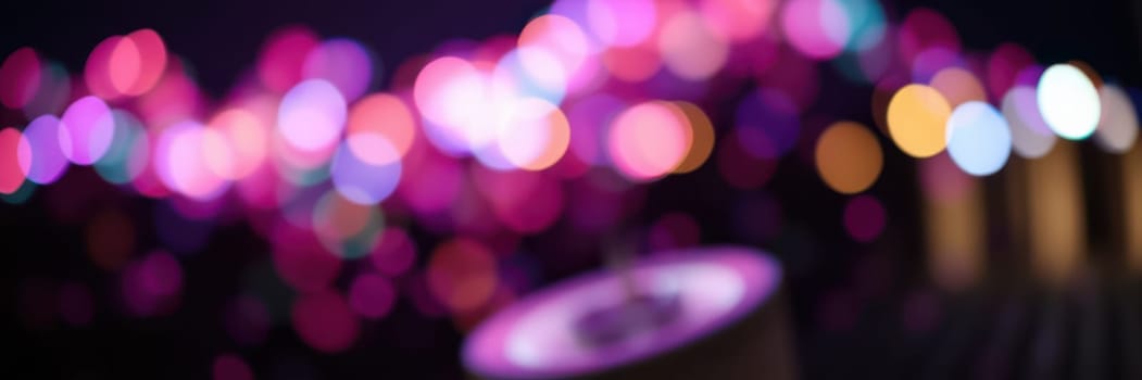 Colorful lights illuminate a festive evening gathering with people enjoying music, food, and camaraderie, creating an enchanting atmosphere filled with joy and excitement.