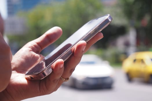 A hand firmly gripping a smartphone while navigating through busy city traffic and vehicles