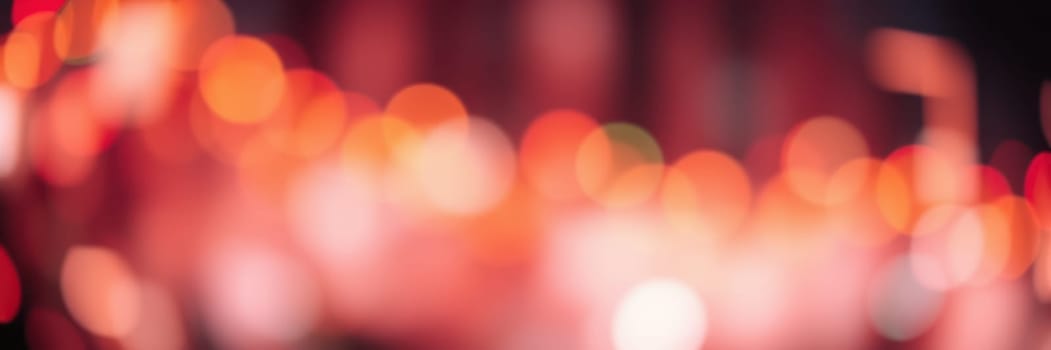 Bright, soft lights blur together, creating a warm and inviting ambiance in the heart of a city at night. The vibrant colors enhance the festive mood among the crowd.