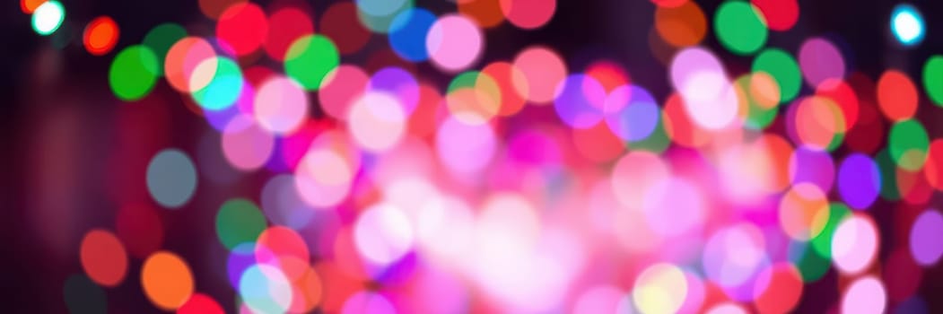 Vibrant bokeh lights illuminate the scene, creating a joyful ambiance at a nighttime event in the city. The colorful display enhances the festive mood, attracting onlookers.