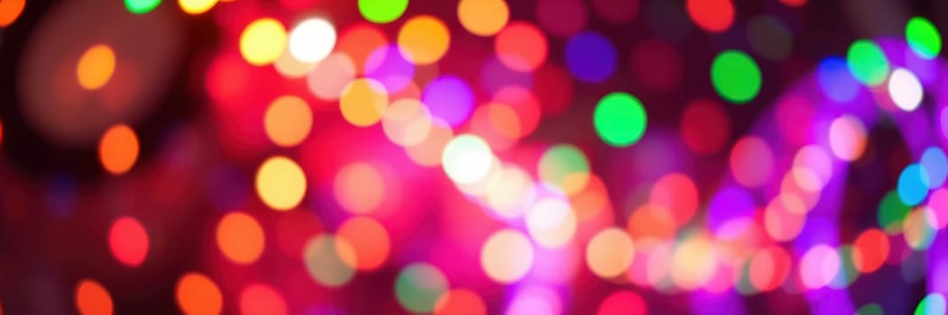 Vibrant lights of various colors fill the air, creating a joyful ambiance at a nighttime celebration in an urban area. People enjoy the lively atmosphere as decorations shimmer.