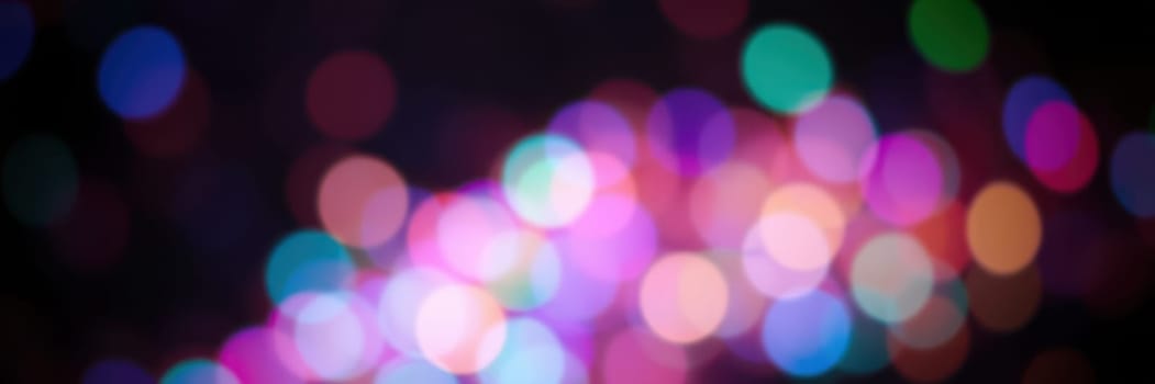 Soft and blurred colorful lights create a festive mood in a bustling urban environment at night. The shimmering hues reflect joy and energy during a lively gathering.