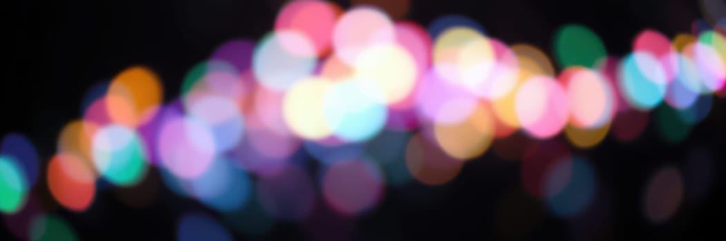 Vibrant, blurred lights create a colorful atmosphere at a nighttime event, as people gather, celebrate, and enjoy the festive ambiance in an outdoor location.