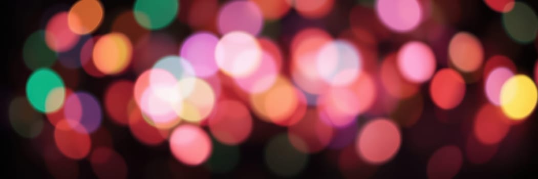 Bright, multicolored lights blur together, filling the background with a vibrant array of colors, enhancing the joyful ambiance of a nighttime celebration.