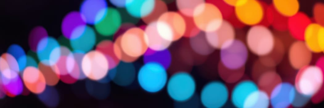 Bright, multicolored lights blur together, creating a lively atmosphere for a celebration in a city park during the evening. People gather to enjoy the festive ambience.